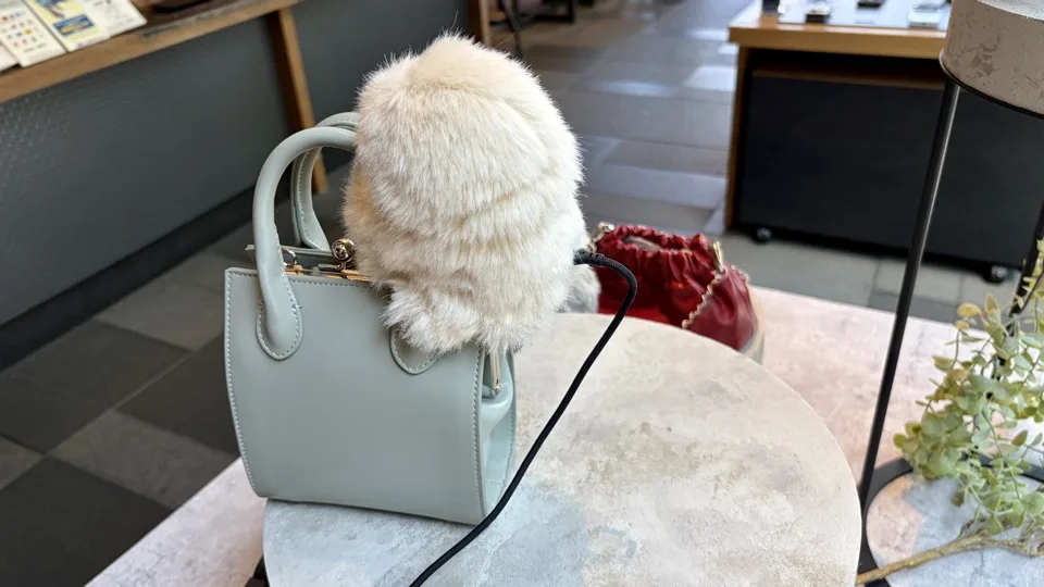 白いバッグにアイボリーのミルミがしがみついている様子